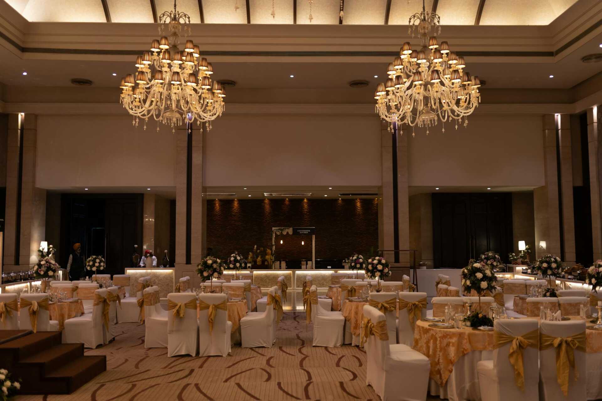 Luxurious ballroom decorated with grand chandeliers and floral arrangements for an elegant event.